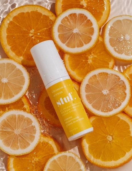 A high-quality product shot of a Vitamin A+E serum bottle surrounded by sliced citrus fruits, emphasizing ingredient freshness and vitality.
